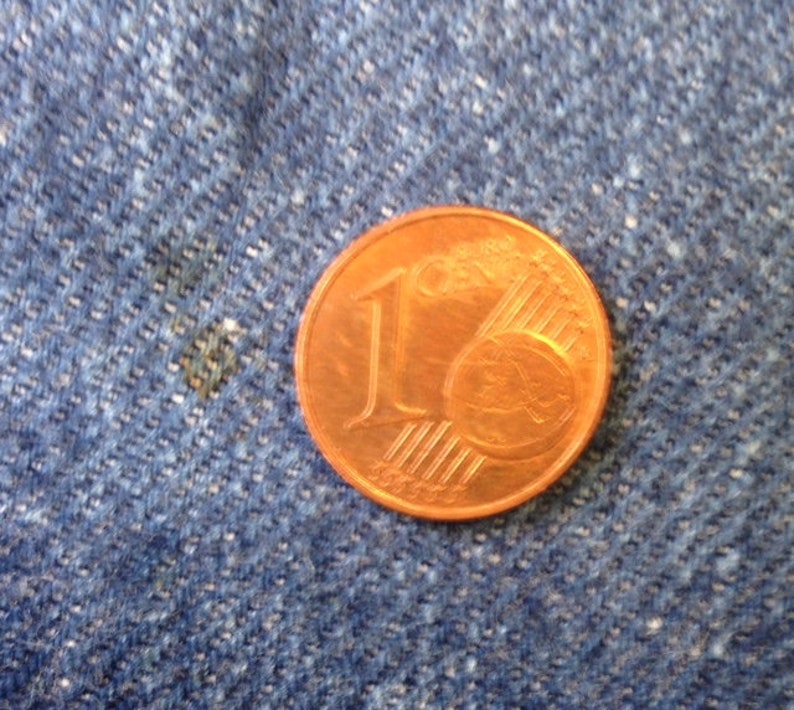 May include: A copper-colored one-cent Euro coin featuring the numeral one and a globe graphic with six parallel lines. The coin is circular with a smooth edge and displays the text 1 Euro Cent clearly on its metallic surface.