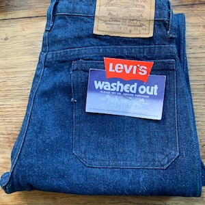 Peut inclure: Un jean bleu denim avec une étiquette Levi's indiquant "washed out" et "Veuillez essayer avant d'acheter". Le jean porte une étiquette Levi Strauss & Co. avec la taille 679 04 17 31 W.