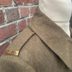 May include: A brown wool coat with a high collar and a gold braid on the shoulder.