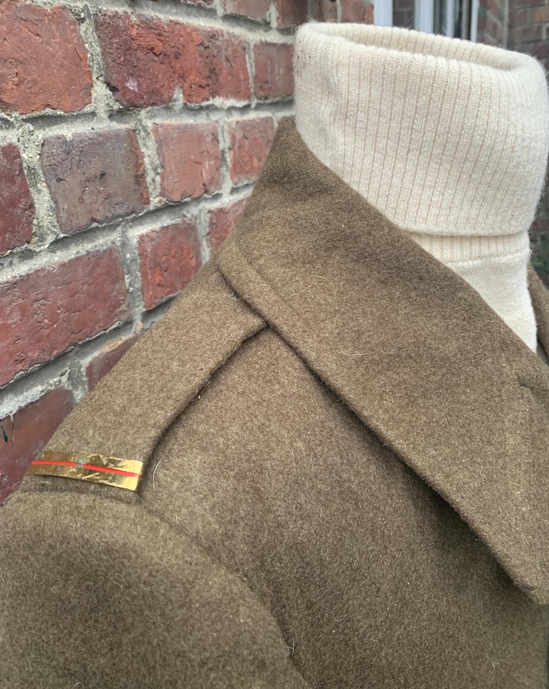 May include: A brown wool coat with a high collar and a gold braid on the shoulder.