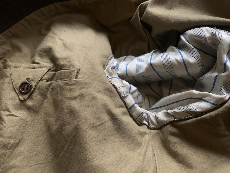 May include: A close-up of the inside of a brown jacket, showing the lining with a white and blue striped pattern.