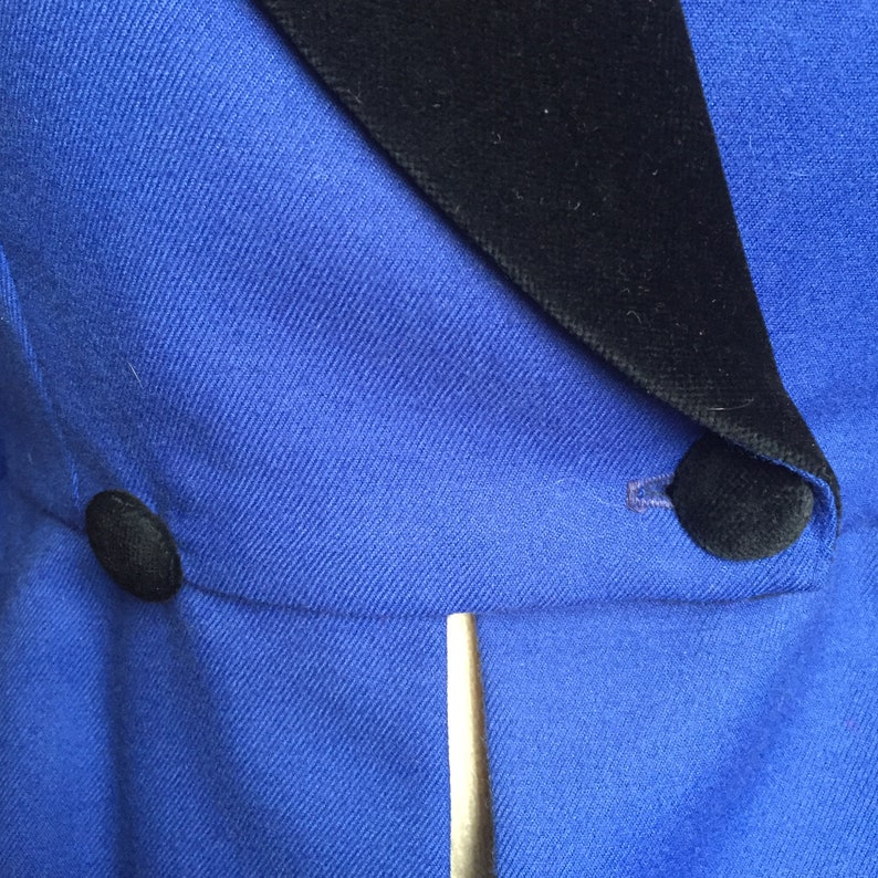 May include: A blue blazer with a black velvet collar and two black buttons. The blazer has a single gold button on the front.