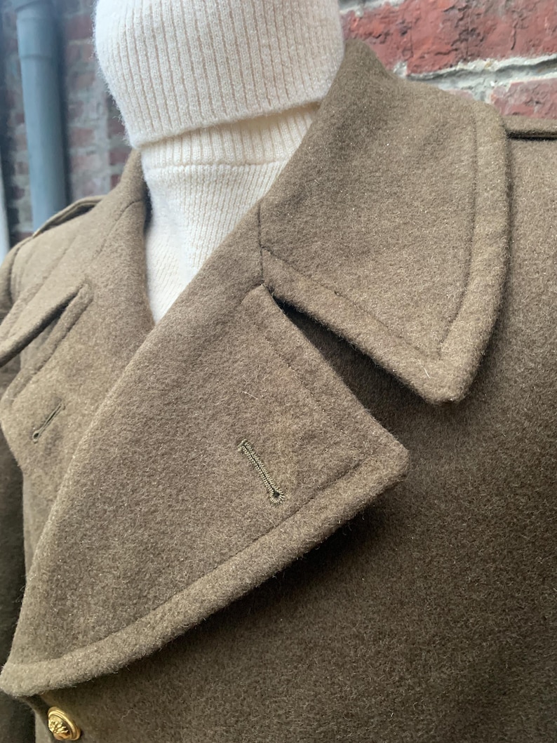 May include: A brown wool coat with a large collar and a button closure. The coat has a textured surface and a single button on the front.