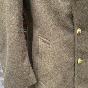 May include: A brown wool peacoat with a double breasted closure and gold buttons. The coat has a flap pocket on the right side.