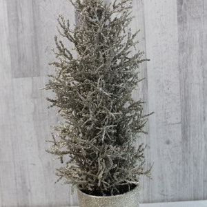 Könnte beinhalten: Ein kleiner, silberner Glitzer-Kunstweihnachtsbaum in einem silbernen Glitzertopf.