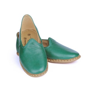 May include: A pair of green leather slip-on shoes with a brown sole.