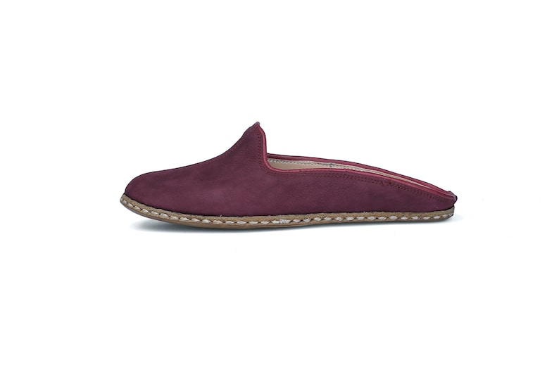 May include: Burgundy suede leather mule with a brown stitched sole.
