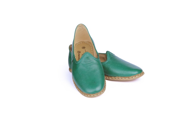 May include: A pair of green leather slip-on shoes with a brown sole.