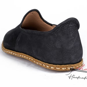 Puede incluir: Zapatos negros de cuero con suela cosida marr&oacute;n. Los zapatos tienen una punta redonda y un dise&ntilde;o sencillo.