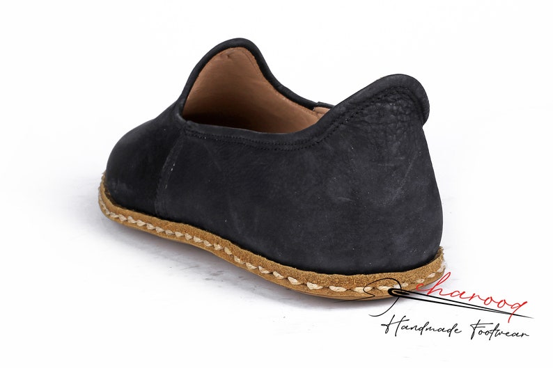 Puede incluir: Zapatos negros de cuero con suela cosida marr&oacute;n. Los zapatos tienen una punta redonda y un dise&ntilde;o sencillo.
