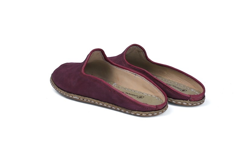 May include: A pair of burgundy leather slippers with a stitched edge and a brown sole.