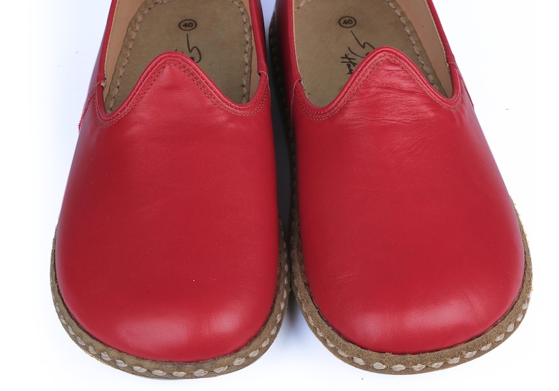 Puede incluir: Primer plano de dos zapatos rojos de cuero. Los zapatos tienen una puntera redondeada y una suela cosida de color marr&oacute;n claro. El interior es de color marr&oacute;n claro. Los zapatos son de la talla 40.