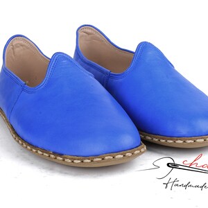 Pu&ograve; includere: Un paio di scarpe blu in pelle da infilare con un bordo cucito marrone. Le scarpe sono fatte a mano e hanno uno stile casual e comodo.