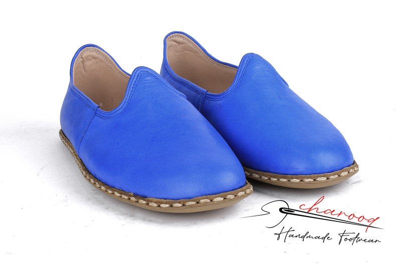 Pu&ograve; includere: Un paio di scarpe blu in pelle da infilare con un bordo cucito marrone. Le scarpe sono fatte a mano e hanno uno stile casual e comodo.