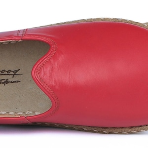 Puede incluir: Una zapatilla de cuero rojo con punta redondeada y suela separada de color beige. La zapatilla tiene el texto "Scharoof Handmade Footwear" impreso en el interior. La suela est&aacute; cosida a la parte superior del zapato con hilo blanco.