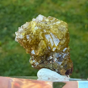 May include: A cluster of translucent, yellow-green mineral crystals with sharp, angular facets. The specimen features a dense arrangement of pointed crystalline structures that vary in clarity, transitioning from pale yellow to deeper olive tones.
