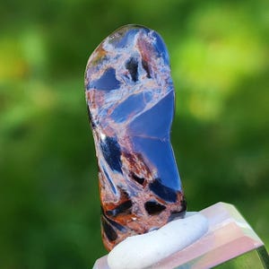 May include: A blue and brown tiger's eye gemstone with a unique swirling pattern. The gemstone is polished and has a smooth, glossy finish.