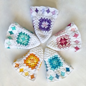 May include: Six crocheted granny square hats in different colors, including purple, teal, pink, orange, blue, and white.