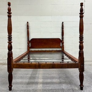 May include: A wooden bed frame with turned posts and a headboard. The bed frame is made of dark wood and has a simple design.