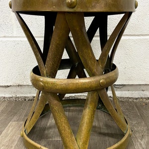 May include: A brass stool with a woven design and studded accents. The stool has a round top and a wide base.