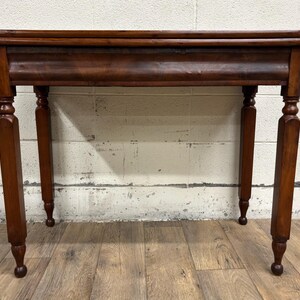 May include: A dark brown wooden table with a rectangular top and four turned legs. The table has a decorative apron and a classic design. The table is approximately 30 inches long, 15 inches wide, and 30 inches tall.