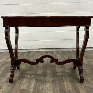 May include: A dark brown wooden console table with a rectangular top and ornate, curved legs. The table has a simple, elegant design.