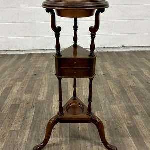 May include: A wooden triangular stand with a copper bowl on top and two drawers. The stand has three legs with a curved design.