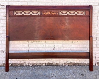 May include: A dark wood headboard with a carved design at the top. The headboard is in good condition with some minor wear and tear.