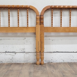 May include: Two wooden headboards with a light brown finish. Each headboard features a curved top with decorative spindles and a lower horizontal support. The headboards are designed for a bed frame and have metal brackets for attachment.