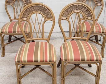 May include: Set of five rattan chairs with arched backs and striped seat cushions. The chairs have a natural wood finish and feature a woven design on the backrests. The seat cushions display a pattern of red, orange, and brown stripes.