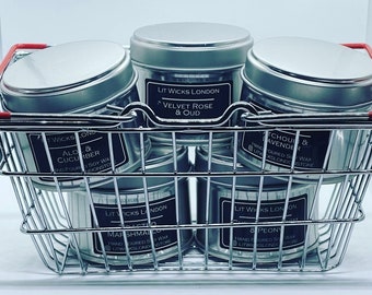 May include: A silver shopping basket filled with six silver candle tins. The labels on the tins read "Lit Wicks London" and list various scents, including "Velvet Rose & Oud", "Marshmallow", "Aloe & Cucumber", "Patchouli & Lavender", and "8 Peony".