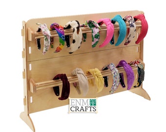 Könnte beinhalten: Ein Holz-Kopfband-Display mit zwei Reihen bunter Kopfband. Der Ständer ist aus hellem Holz und hat ein schlichtes Design. Die Kopfband sind in verschiedenen Farben und Mustern, darunter Blumen, Punkte und Uni-Farben. Der Ständer ist mit "ENM CRAFTS" beschriftet.
