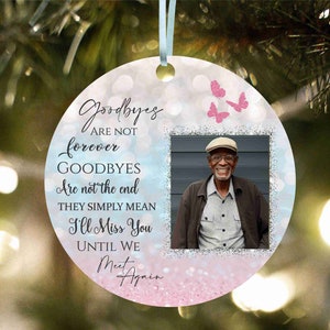 May include: A pink and blue glitter background with a photo frame in the centre. The frame contains a photo of a man wearing a hat and smiling. The text "Goodbyes are not forever, Goodbyes are not the end, They simply mean I'll Miss You Until We Meet Again" is written in black text on the background.