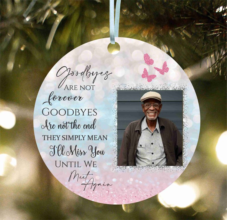 May include: A pink and blue glitter background with a photo frame in the centre. The frame contains a photo of a man wearing a hat and smiling. The text "Goodbyes are not forever, Goodbyes are not the end, They simply mean I'll Miss You Until We Meet Again" is written in black text on the background.