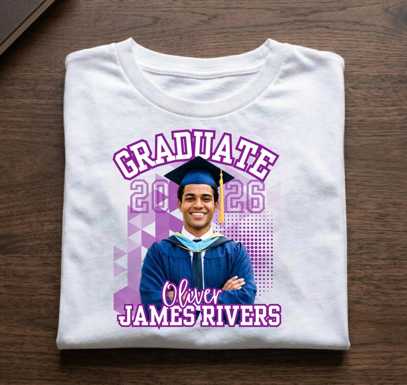 May include: White t-shirt with a graduation design. The design includes the word "GRADUATE" in purple, the year "2026", and a photo of a graduate in a cap and gown. The graduate's name, "Oliver JAMES RIVERS", is also printed on the shirt.