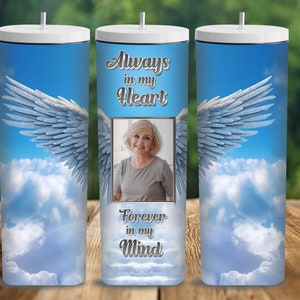 Könnte beinhalten: Ein weißer Becher mit einem Hintergrund aus blauem Himmel und weißen Wolken. Der Becher hat ein Bild einer Frau mit dem Text "Always in my Heart, Forever in my Mind".