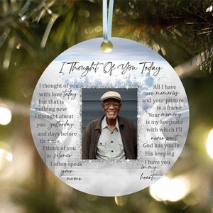 May include: A white round bauble with a blue and silver glitter background. The ornament features a photo of an older man wearing a hat and a message that reads "I Thought Of You Today". The message continues with a poem about remembering someone who has passed away.