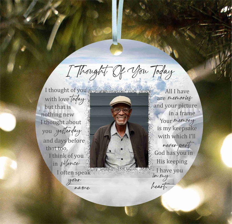 May include: A white round bauble with a blue and silver glitter background. The ornament features a photo of an older man wearing a hat and a message that reads "I Thought Of You Today". The message continues with a poem about remembering someone who has passed away.