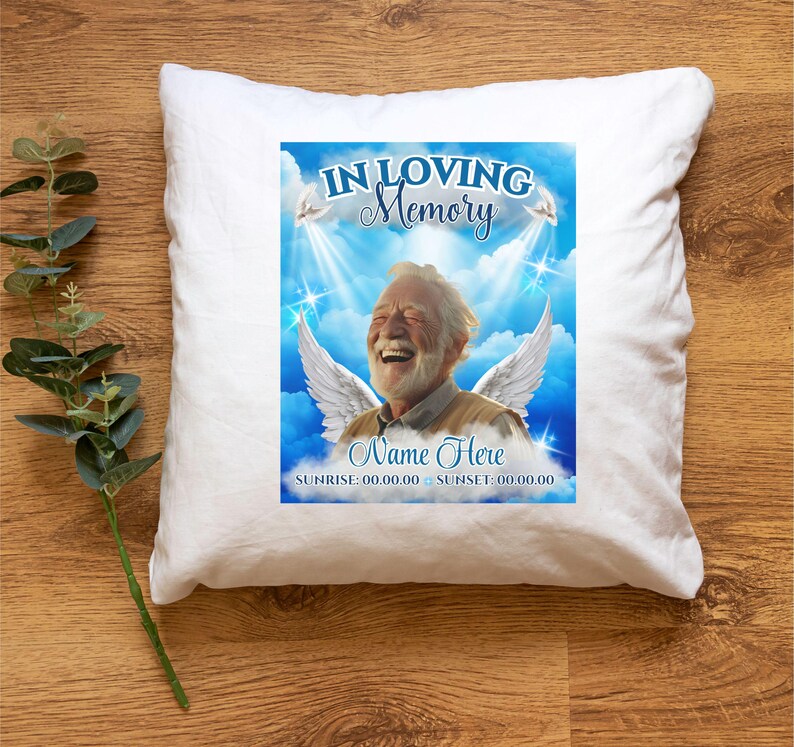 Puede incluir: Almohada blanca con un dise&ntilde;o impreso en azul y blanco. El dise&ntilde;o presenta a un hombre con alas, nubes y estrellas. El texto dice "In Loving Memory", "Name Here", "Sunrise: 00.00.00 Sunset: 00.00.00".