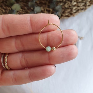 Puede incluir: Un aro de oro para la oreja con una peque&ntilde;a piedra verde y una perla dorada.