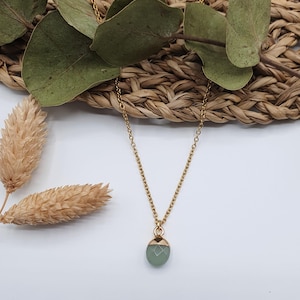Puede incluir: Un collar de cadena dorada con un colgante de piedra preciosa verde claro.