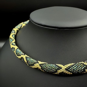 Peut inclure: Un collier de perles noires et dorées avec un motif géométrique. Le collier est composé de petites perles irisées qui créent un effet chatoyant.