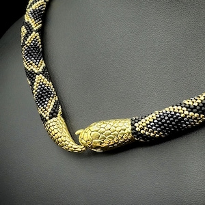 May include: A black and gold beaded snake necklace with a gold snake head clasp.