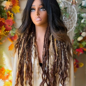 May include: A mannequin head with a black and brown ombre wig featuring long, wavy hair and dreadlock extensions in shades of brown and blonde. The wig is styled with a deep part and layered strands.