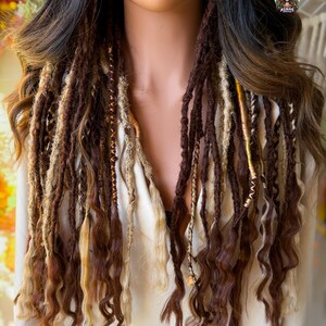 May include: A mannequin displays a set of brown and blonde dreadlocks with curly ends. The dreadlocks are a mix of dark and light brown, with some strands featuring gold accents. The hair is styled to fall over the shoulders.
