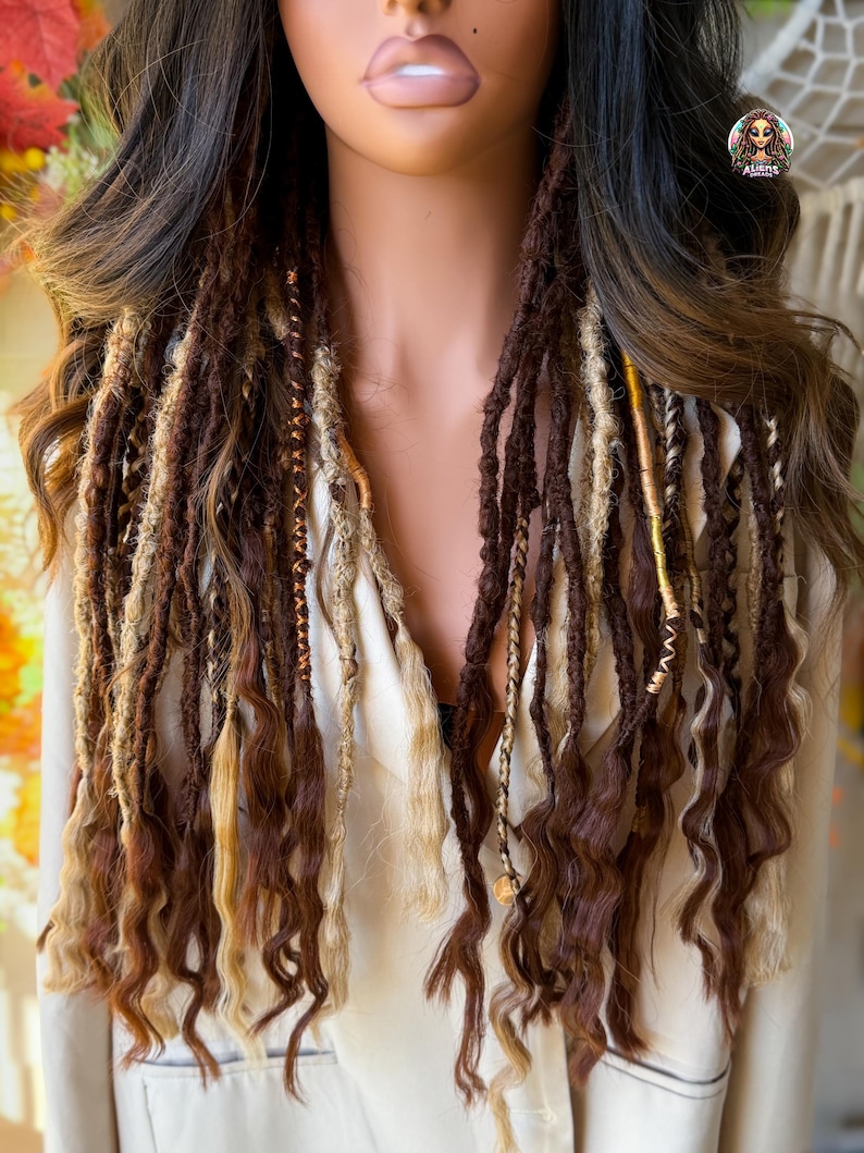 May include: A mannequin displays a set of brown and blonde dreadlocks with curly ends. The dreadlocks are a mix of dark and light brown, with some strands featuring gold accents. The hair is styled to fall over the shoulders.