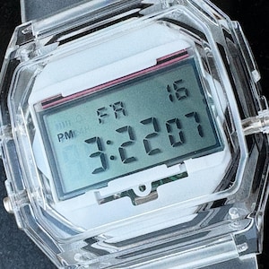 以下が含まれることがあります： 白文字盤と長方形のディスプレイを備えた、透明なデジタル時計。 金曜日の16日、午後3時22分7秒を表示します。 透明なバンドと透明な八角形のケースを備えた時計です。