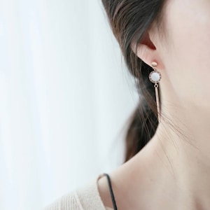 May include: A pair of gold-tone drop earrings with a white round stone and a long, thin, gold-tone chain.