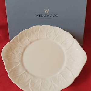 May include: A white ceramic plate with a leaf design around the edge. The plate is round with a slightly irregular shape. The Wedgwood logo is visible in the background.