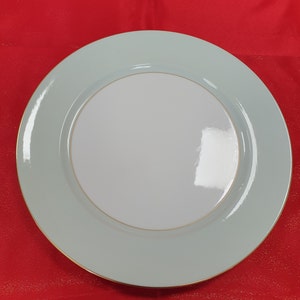 May include: A light blue charger plate with a gold rim. The plate is made of ceramic and has a glossy finish.